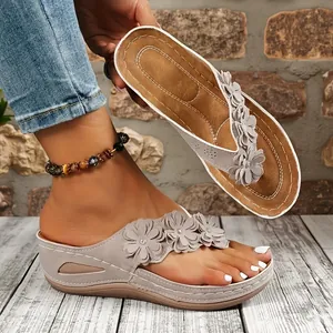 Vista detallada de chanclas de cuña grises con delicados adornos de flores 3D
