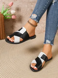 Detailansicht der stylischen schwarz-weißen flachen Pantoletten am Fuß des Models