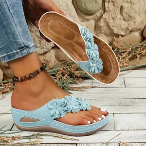Detalle de chanclas con cuña azul claro con adornos florales 3D y costuras de estilo vintage
