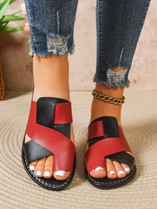 Nahaufnahme der modischen zweifarbigen flachen Zehenring-Sandalen in Rot und Schwarz an einem Modell