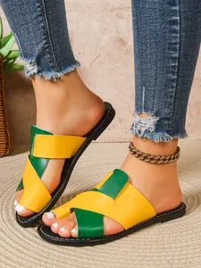 Detailansicht der gelb-grünen Color-Block-Flachsandale für Damen an den Füßen eines Modells