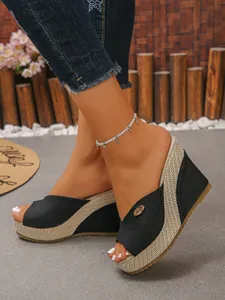 Gedetailleerde weergave van zwarte stoffen sandalen met sleehak en geweven platform en open teen.
