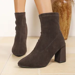Elegante braune Wildleder-Stiefeletten mit bequemem Blockabsatz, an Füßen gezeigt