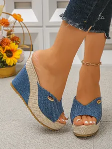 Detailopname van stijlvolle blauwe denim sleehak sandalen met een geweven strozool
