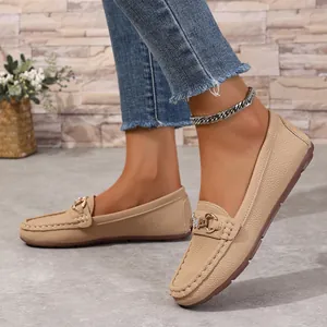 Side view detail of beige textured leather loafers with gold metal buckle decoration