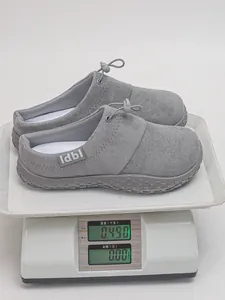 Close-up of grey suede slip-on shoes being weighed on a white digital kitchen scale.