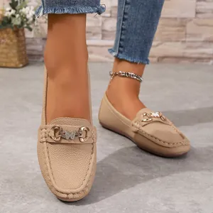 Detailed view of beige pebbled leather loafers with stylish butterfly metal buckle