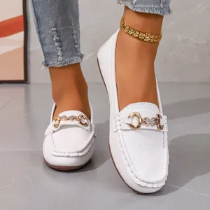 Detail shot of white pebbled leather loafers with golden butterfly buckle for women