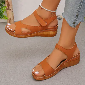 Detailopname van bruine sandalen met sleehak, witte stiksels en klittenband aan de voeten