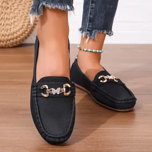 Detailed view of black leather loafers with gold butterfly metal buckle accents.