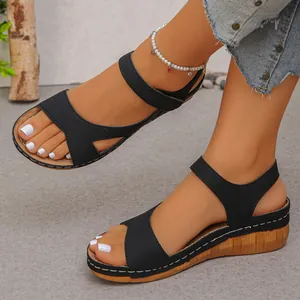 Gedetailleerde weergave van zwarte sleehaksandalen met witte stiksels en klittenband