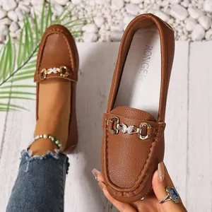 Close-up of brown leather loafers featuring gold metal buckle and pebbled texture