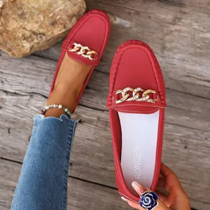 Detailed macro shot of stylish red leather loafers with rhinestone gold chain buckle