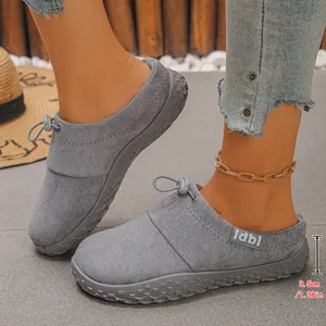 Close-up detail of grey suede slip-on shoes with 3.5cm wedge sole and lace accent