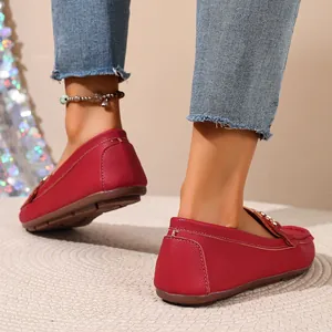 Detailed rear view of red vintage loafers with metal buckle on a woven rug background.