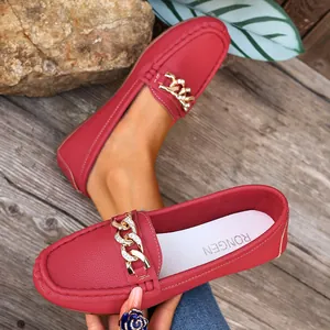 Detailed view of red leather loafers with elegant gold chain buckle and textured finish
