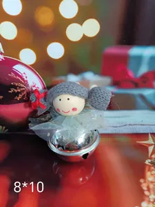 Detailed view of Christmas doll ornament with gray knit hair and silver bell body