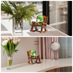 Detailed view of a cute green frog reading a book on a wooden rocking chair ornament.