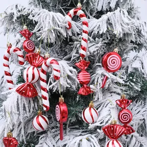 Close-up of red and white candy-shaped Christmas tree ornaments on snowy branches