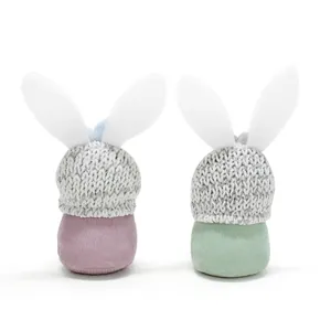 Detailansicht der Rückseite von Osterhasen-Gnom-Puppen mit grauen Strickmützen und Stoff