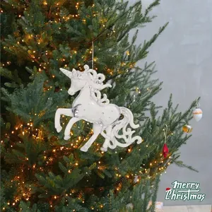Detailed view of a clear acrylic unicorn hanging ornament on a lit Christmas tree