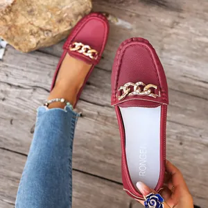 Close-up detail of burgundy red leather loafers featuring gold chain and rhinestone buckle