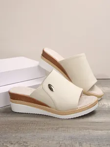 Détail de mules compensées beiges pour femmes avec semelle plateforme et logo métal