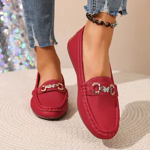 Close-up of red pebbled leather loafers with golden butterfly horsebit buckle detail