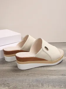 Vue latérale détaillée de mules compensées beiges pour femmes avec bride en tissu et semelle.