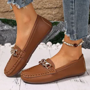 Close-up view of women's brown retro loafers with sparkling metal chain buckle decoration