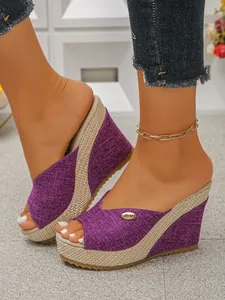 Close-up van paarse sleehak slippers met open neus en geweven espadrille plateauzool
