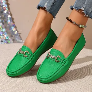 Detail view of vibrant green pebbled leather loafers with a classic gold metal bit