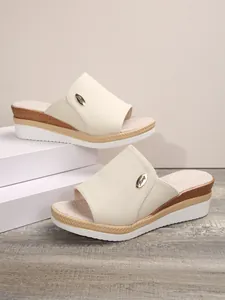 Gros plan de mules compensées en toile blanc cassé avec semelle plateforme et logo.