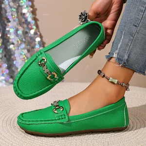 Detail view of vibrant green loafers with textured leather and a stylish metal buckle.