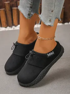 Close-up of stylish black suede loafers with toggle tie detail and gold anklet decor