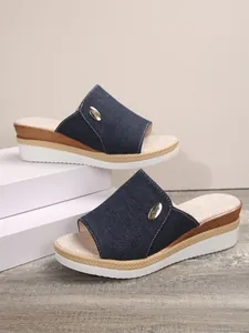 Vue détaillée des mules compensées en denim bleu foncé pour femmes avec emblème doré