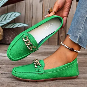 Detail of vibrant green leather loafers with decorative gold metal chain and rhinestones.