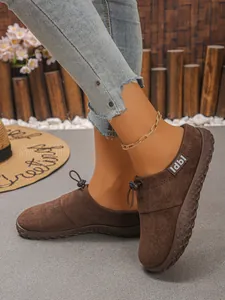 Close-up detail of women's brown suede flat shoes featuring a front drawstring toggle closure