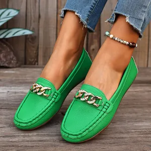 Close-up view of vibrant green leather loafers featuring a sparkling gold chain buckle accent