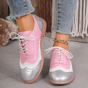 Primer plano de zapatos Brogue rosas con punta redonda y diseño de cordones blancos.