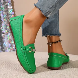 Close-up detail of vibrant green pebbled leather loafers featuring a golden horsebit buckle
