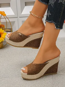 Gedetailleerd overzicht van bruine sleehak sandalen voor dames met gevlochten stro details.