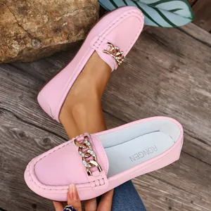 Detailed view of pink leather loafers featuring a decorative gold chain and sparkling crystals