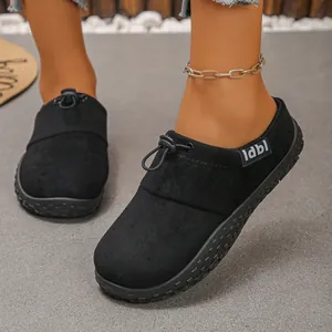 Close-up detail of black suede single shoes featuring bungee cord and side label