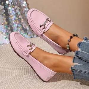 Close-up of pink leather loafers with decorative metal buckle and crystal detail