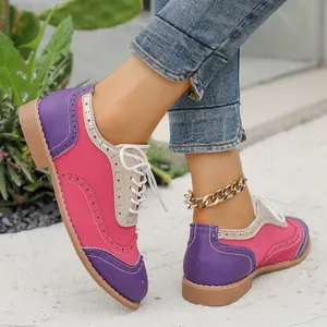 Primer plano de zapatos Brogue coloridos con detalles perforados y cordones blancos.