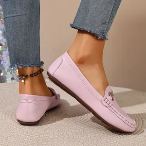 Close-up of stylish pink leather loafers with metal buckle detail on a textured mat