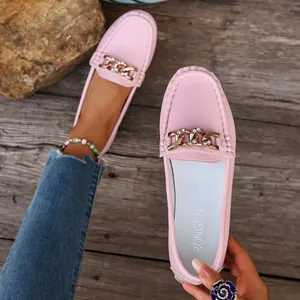 Close-up of pink leather loafers featuring a decorative gold metal chain and buckle