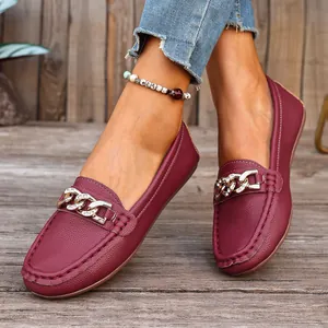 Close-up of stylish wine red leather loafers featuring gold chain rhinestone buckle