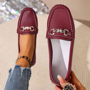Detailed macro view of burgundy pebbled leather loafers with silver rhinestone buckle